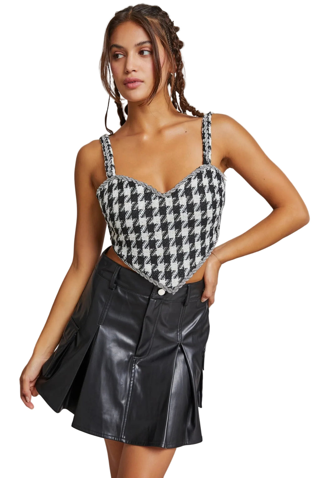 Woman wearing a houndstooth pattern top and black leather skirt against a plain background