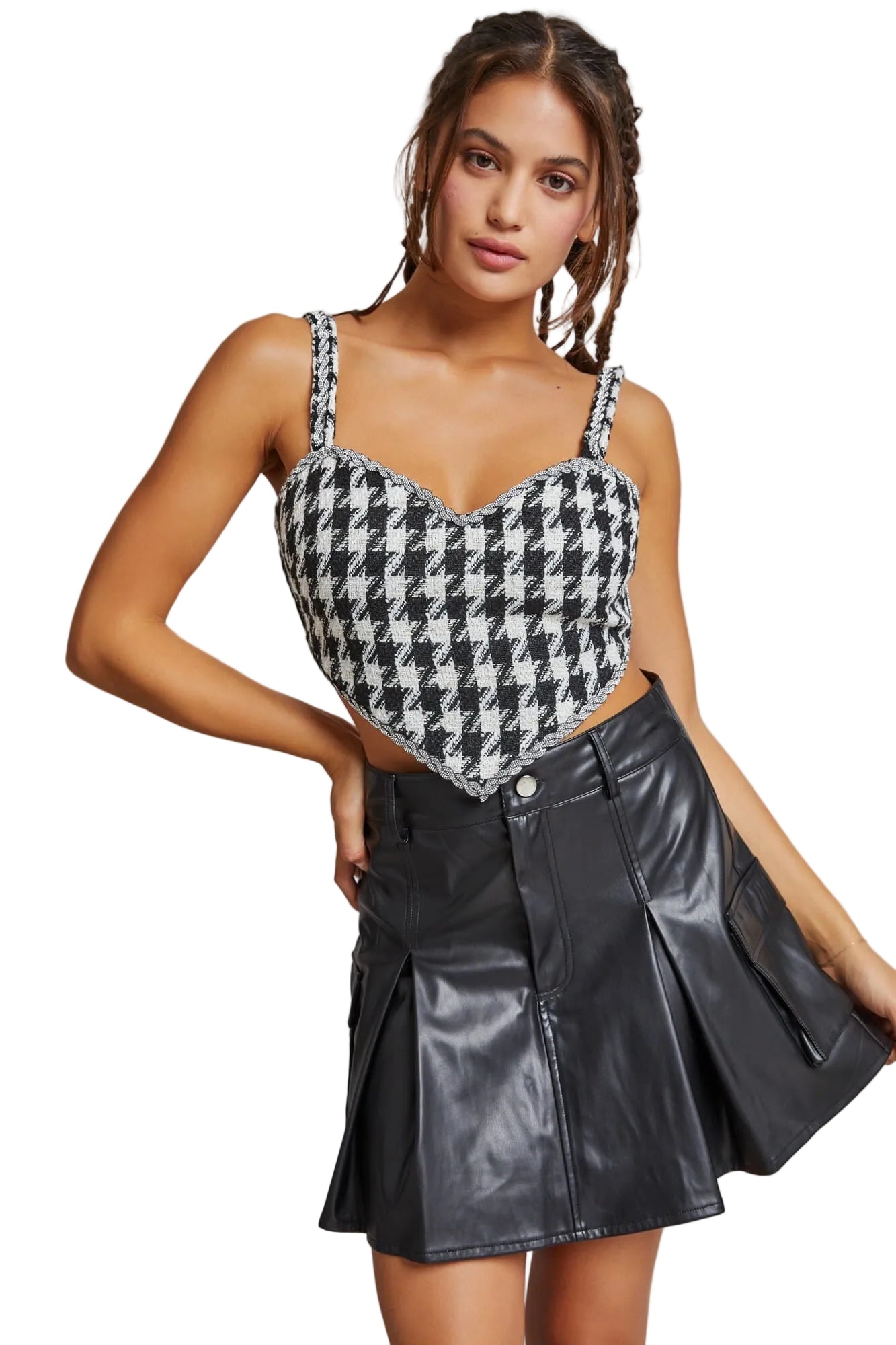 Woman wearing a houndstooth pattern top and black leather skirt against a neutral background
