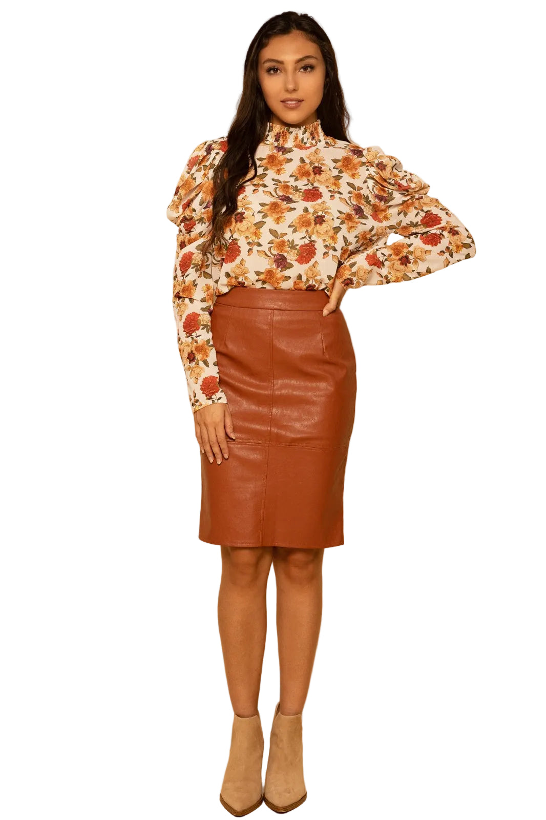 Woman wearing a floral blouse and brown leather skirt against a beige background