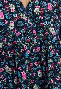 Close-up of a dark navy floral dress or top with a dense multicolor floral print featuring pink, blue, white, and red blossoms.