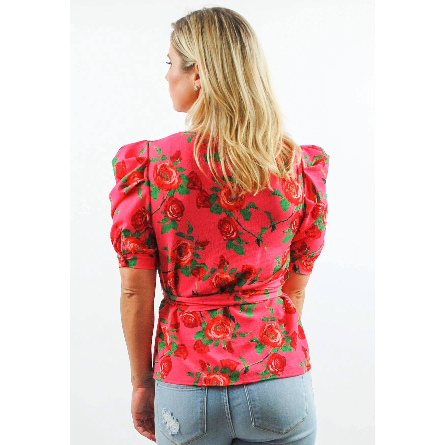 Woman wearing a red floral blouse with puffed sleeves on a white background