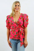 Woman wearing a pink floral top with blue jeans on a white background