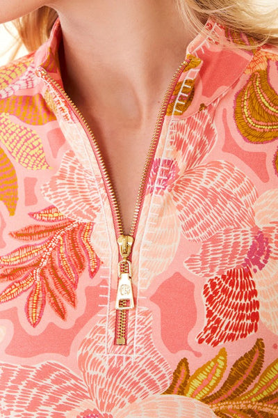 Close-up of a model wearing a pink and orange floral print quarter-zip jacket with a gold zipper pull.