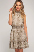 Woman wearing a snake print dress on a plain background